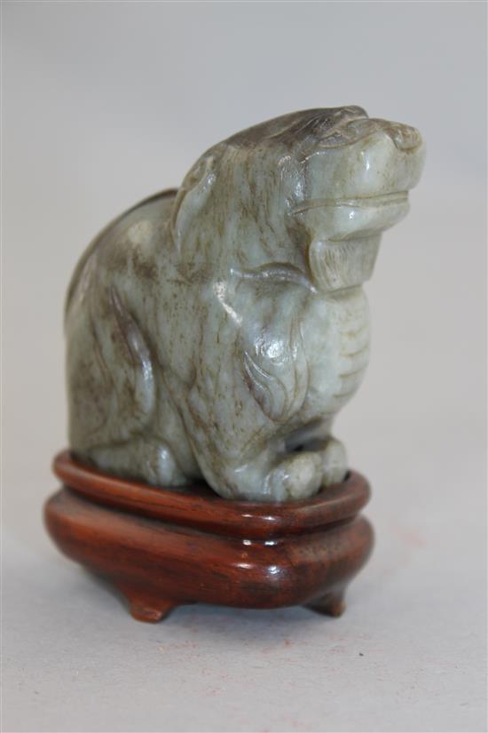 A Chinese pale grey and black jade carving of a lion-dog, Ming dynasty, 6cm., wood stand